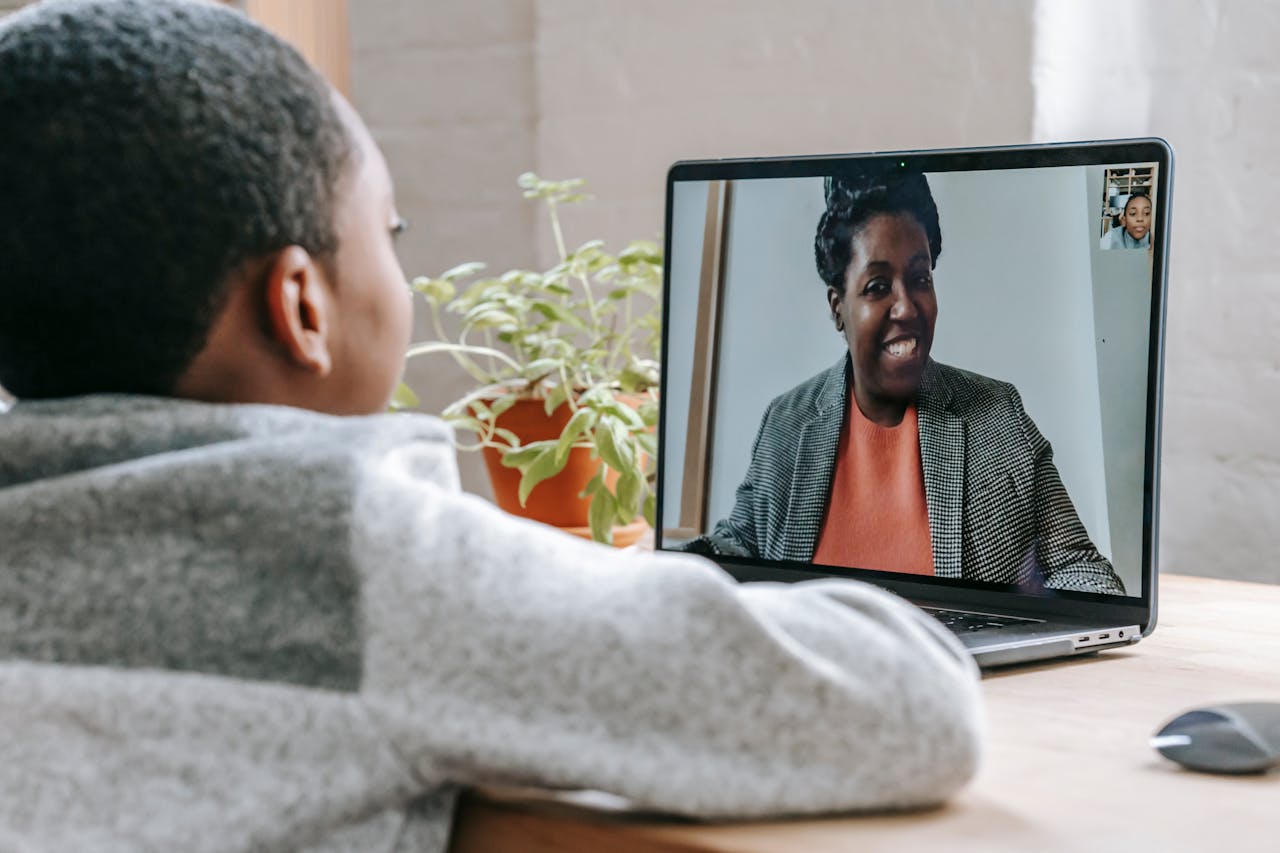 A young boy participates in online learning through a video call on his laptop.